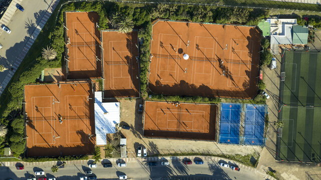 Aerial view of the tennis courts at the Yacht Club Uruguayo with clay and hard surfaces, surrounding greenery, and nearby street parking in Montevideo, Departamento de Montevideo, Uruguay.
