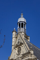 Fototapeta premium Historic Saint Etienne du Mont church in Paris features an ornate stone facade, bell tower and decorative architecture rising against a clear deep blue summer sky.