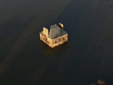 Coueron, France - 29 December 2025: Aerial view of La Maison dans la Loire, a surreal house sculpture partially submerged in the river, captured from a high angle during golden hour.