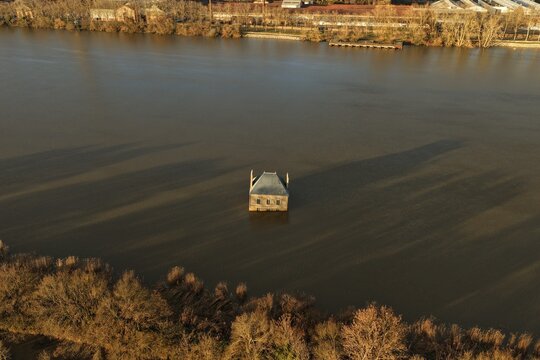 Coueron, France - 29 December 2025: Aerial view of La Maison dans la Loire, a surreal house sculpture partially submerged in the river, surrounded by calm water and trees.