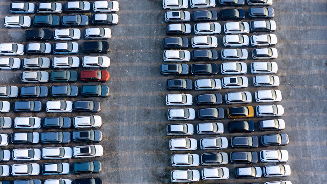 Piacenza, Emilia-Romagna, Italy - 01 August 2026: Aerial view of a car parking factory yard filled with rows of new vehicles parked in an organized grid pattern on asphalt.