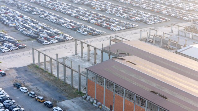 Piacenza, Italy - 01 August 2026: Aerial view of a car parking factory yard with rows of parked vehicles, industrial buildings, and concrete surfaces.