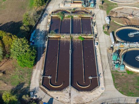 Farnham, England, United Kingdom - 15 September 2026: Aerial view of the waste water treatment works featuring large aeration tanks and circular clarifiers surrounded by green space.