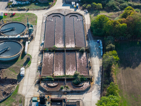 Farnham, United Kingdom - 15 September 2026: Aerial view of the Waste Water Treatment Works with aeration tanks and circular sedimentation basins surrounded by industrial infrastructure.