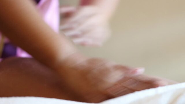 A therapist applying body scrub cream to a woman's leg during a traditional Thai massage