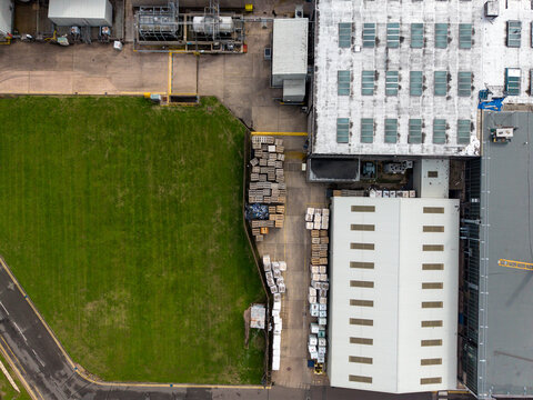 Stafford, England, United Kingdom - 13 September 2026: Aerial view of the Bostik factory, featuring industrial buildings, storage areas with stacked pallets, and a green lawn.