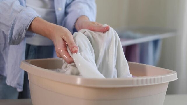 Person hand washing clothes in soapy water, household laundry and fabric care concept