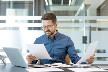 Plakat Corporate productivity and business analysis, professional man reviewing financial documents and reports at office desk with laptop