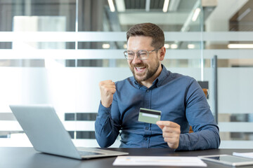 Obraz premium Online shopping success and e-commerce payment, happy man using credit card and laptop for digital transaction in office