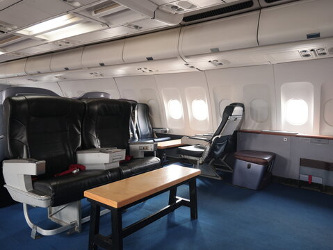 Airplane cabin interior with black leather seats overhead bins large windows tables and aisle in modern jet aircraft cabin