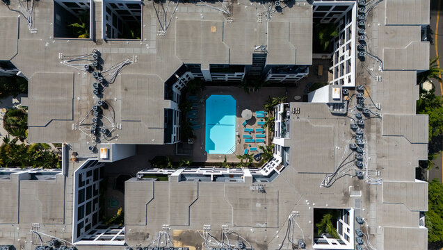 Los Angeles, California, United States - 13 September 2026: Aerial view of Miracle Mile apartment complex with a central swimming pool, surrounded by rooftops and palm trees.