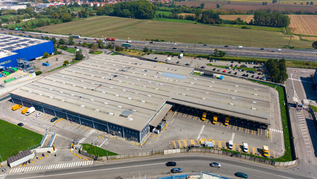 Sesto Ulteriano, Italy - 05 September 2026: Aerial view of the Esselunga Spa logistics facility, featuring a large warehouse, loading docks, and yellow trucks.