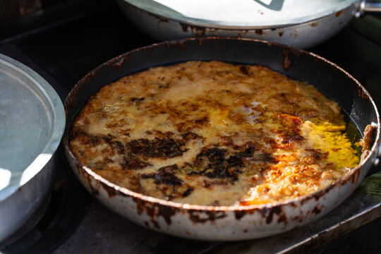cooking traditional Friulian frico in a pan at a village festival