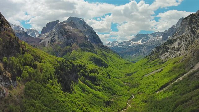 Aerial view of amazing rocky mountains in snow and green valley, Prokletie park, Montenegro and Albania, 4k