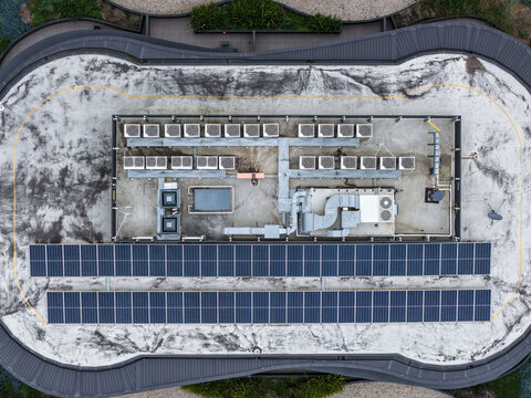 Ringwood, Victoria, Australia - 13 September 2026: Aerial view of a commercial rooftop featuring rows of solar panels and various HVAC ventilation units installed on a flat roof surface.