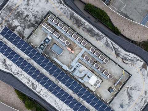 Ringwood, Victoria, Australia - 13 September 2026: Aerial view of a commercial rooftop featuring rows of solar panels and multiple HVAC ventilation units.