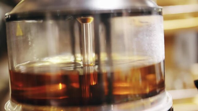 Hot hazlenut brandy beverage warming in a transparent container at a cozy setting, ideal for illustrating drink preparation, specialized equipment, and atmosphere at bars or markets