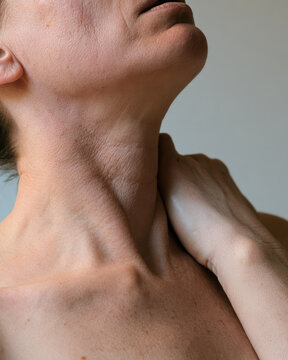 Adult woman clutching throat during allergic reaction with chin raised, visible neck tension, clavicle detail, and realistic skin texture under soft indoor light