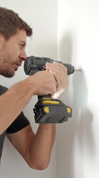 Man drilling hole in wall with cordless power drill. Home improvement and DIY installation concept