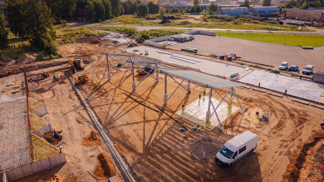 Valmiera, Valmiera Municipality, Latvia - 09 September 2026: Aerial view of a construction site with steel framework, workers, machinery, and industrial building reconstruction.
