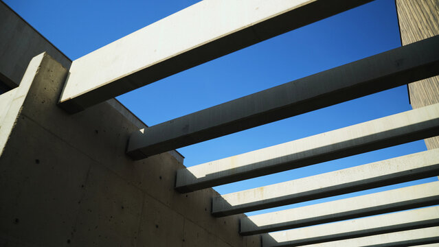 Brutalist architectural building with concrete beams creating geometric patterns against clear blue sky