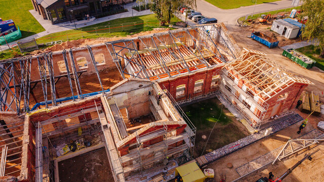 Valmiera, Valmiera Municipality, Latvia - 09 September 2026: Aerial view of a red brick building undergoing reconstruction with wooden roof trusses and scaffolding.