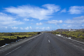 Obraz premium Straight asphalt road through mossy lava field in Iceland winter
