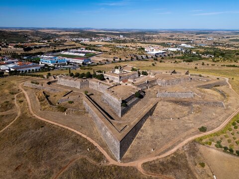 Elvas, Portugal - 10 September 2026: Aerial view of Forte de Santa Luzia, a historic star-shaped fortification surrounded by dry fields and the town landscape under a blue sky.