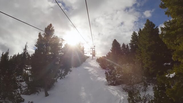 Ski lift ride through snowy slopes and pine forests at sunrise in Borovets, Bulgaria