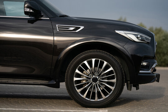 Side view of the front section of a black luxury SUV showing wheel and body lines