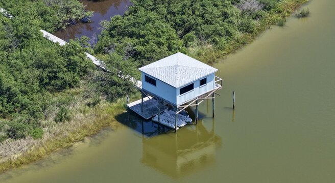 Aerial view of Summer Haven stilt house surrounded by lush coastal vegetation and calm water in St. Johns County, Florida, United States.