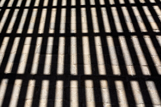 Geometric play of light and shadow creating a rhythmic striped visual effect on outdoor masonry paving.