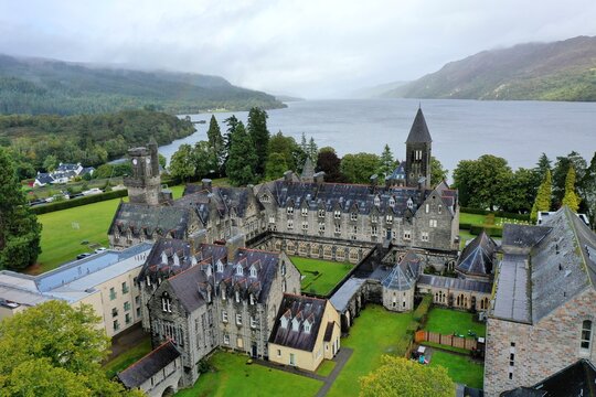 Aerial view of The Highland Club, formerly St Benedict's Abbey, featuring historic stone architecture and green lawns overlooking Loch Ness in Fort Augustus, Scotland, United Kingdom.