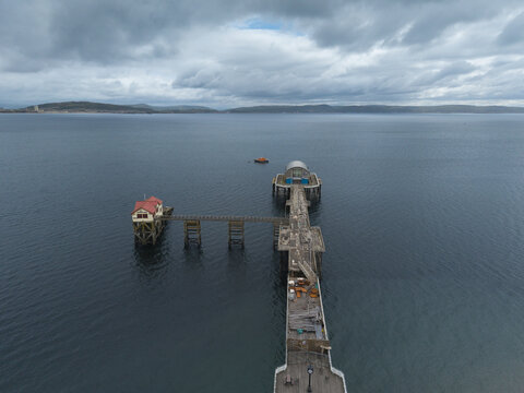 Aerial view of Mumbles Pier extending into the sea under a cloudy sky in Swansea, Wales, United Kingdom.