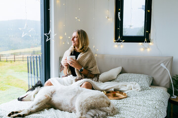Naklejka premium happy woman with dog relaxing in bed at Christmas time