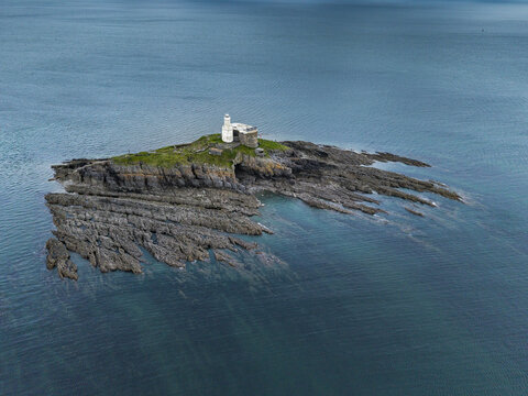 Aerial view of Mumbles Lighthouse situated on a rocky island surrounded by the sea in Swansea, Wales, United Kingdom.