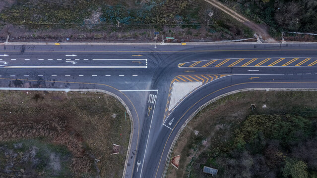 Aerial view of a T-junction road intersection featuring clear lane markings, a stop sign, and asphalt surfaces surrounded by natural vegetation in Johannesburg, Gauteng, South Africa.