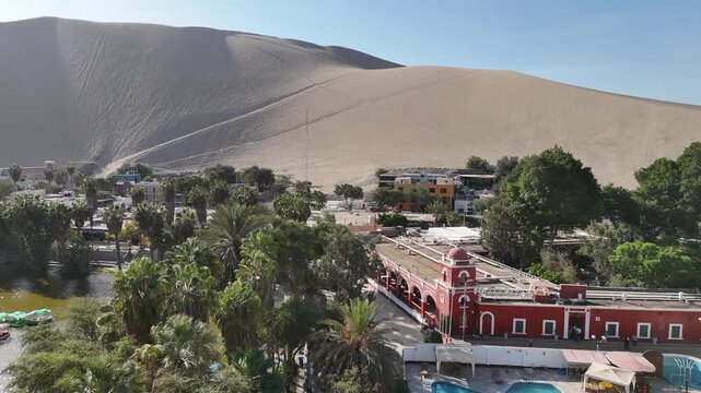 Cinematic aerial view of massive, endless sand dunes towering over the desert landscape in Huacachina, Peru.