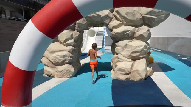 Slow Motion Child Running Toward Water Slide At Outdoor Water Park