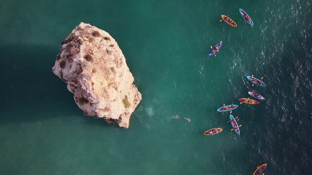 Aerial top down view of kayakers paddling near rock formation