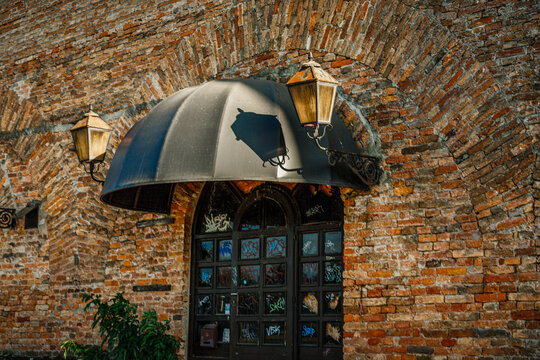 Historic brick building with arches and lanterns near a city street in daylight