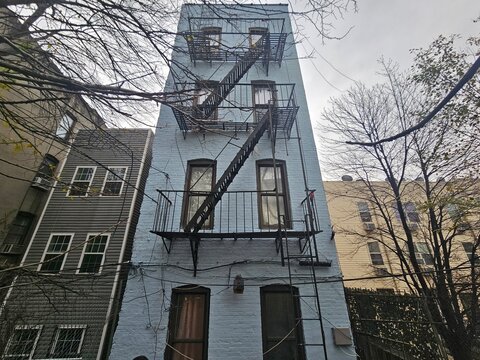 Blue-painted rowhouse rear with layered fire escapes