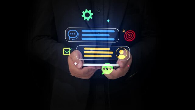 Businessman holding smartphone with digital chat and target icons floating over black background 4k footage 