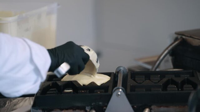 Chef Preparing Fresh Waffle Batter pouring pastry in baker iron in a Professional Kitchen