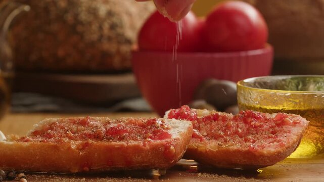 Chef preparing traditional Spanish tomato bread tapas with fresh olive oil and garlic on rustic wooden table