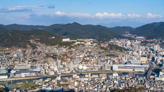 Expansive Nagasaki cityscape and Nagasaki Port framed by clear blue sky from Mount Inasa