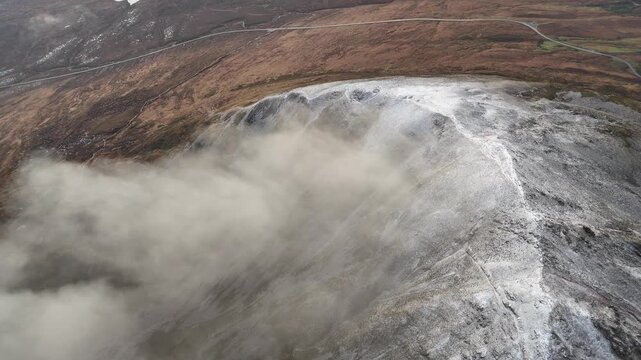 Drone view along the snowy ridge of Errigal with drifting clouds, County Donegal, Ireland