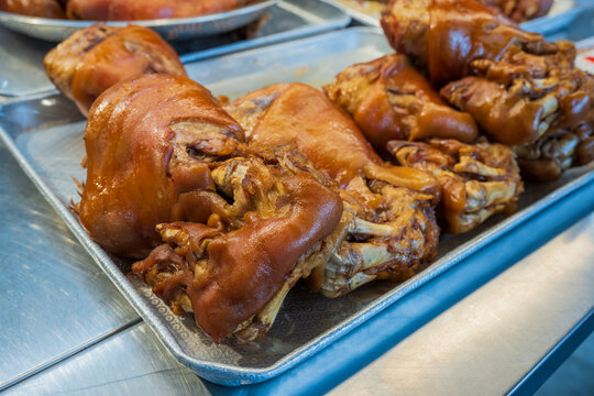Glazed braised pig trotters on a metal tray are displayed for sale at a traditional five day market in South Korea.