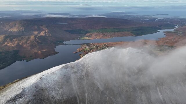 Clouds drifting over the snowy summit of Errigal above lakes, County Donegal, Ireland