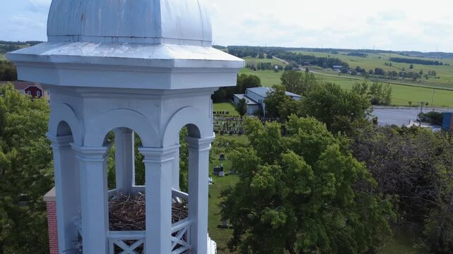 Drone footage passes near a turret on the roof of Saint-Anaclet-de-Lessard church, where a bird nest is visible, before heading toward the village cemetery through the treetops.